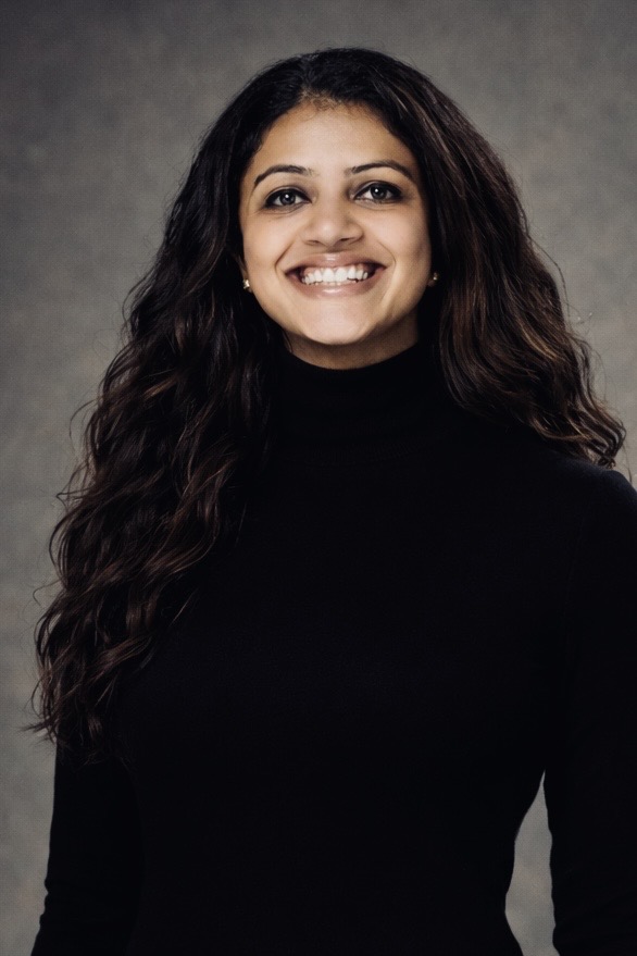 Assistant Professor Abha Rai smiles looking at the camera, wearing a black turtleneck sweater